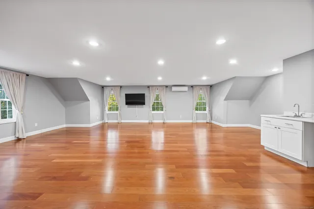 a view of an empty room with kitchen and window