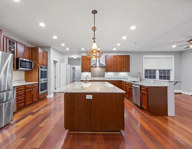 a large kitchen with stainless steel appliances granite countertop a stove and a wooden floors