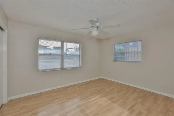 a view of empty room with wooden floor and fan