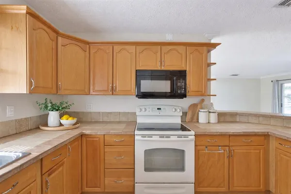 a kitchen with stainless steel appliances granite countertop a sink a stove and a microwave oven with cabinets