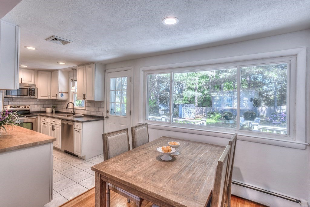 a kitchen with granite countertop a stove a sink a dining table and chairs