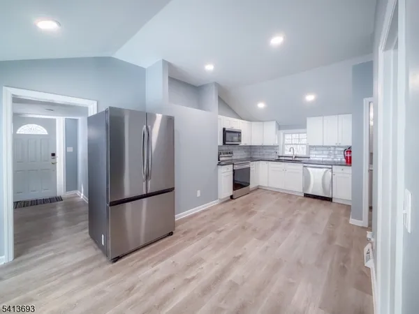 a kitchen with stainless steel appliances granite countertop a sink dishwasher a stove and a microwave oven with cabinets