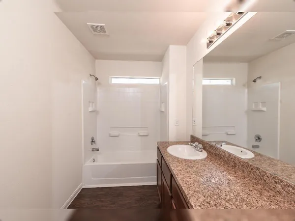 a bathroom with a granite countertop sink a mirror and a bathtub