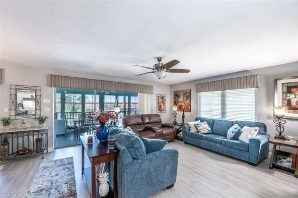 a living room with furniture kitchen view and a wooden floor