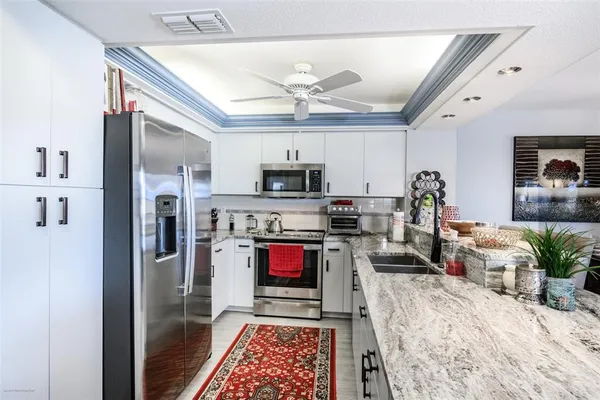 a living room with stainless steel appliances furniture a fireplace and a flat screen tv