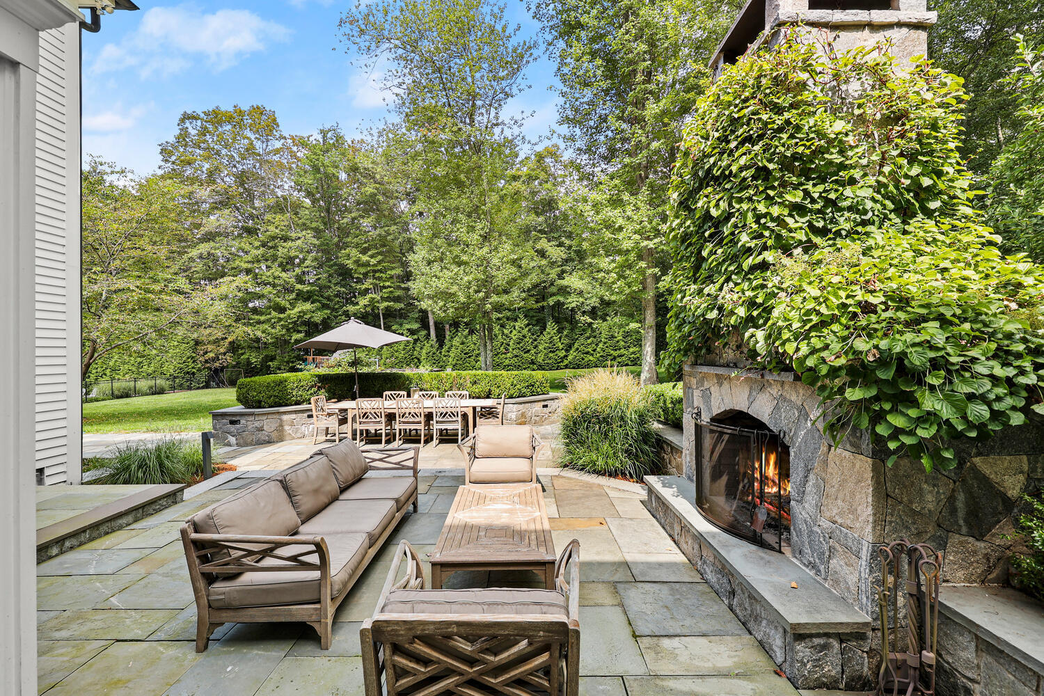 35 Logan Road New Canaan, CT 06840 - Photo 48 of 73 a view of a patio with couches table and chairs under an umbrella with a small garden
