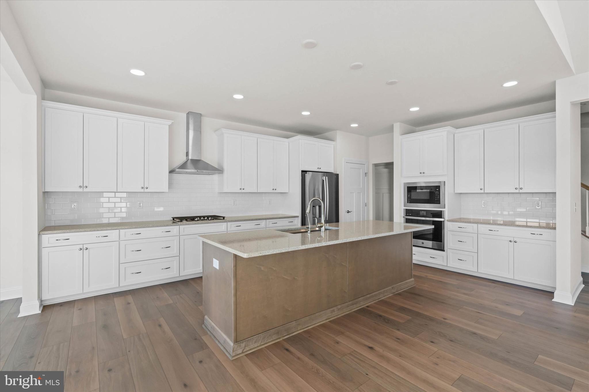 22484 Hummingbird Road, Unit 13 Ellendale, DE 19941 - Photo 13 of 34 a large kitchen with cabinets wooden floor and stainless steel appliances