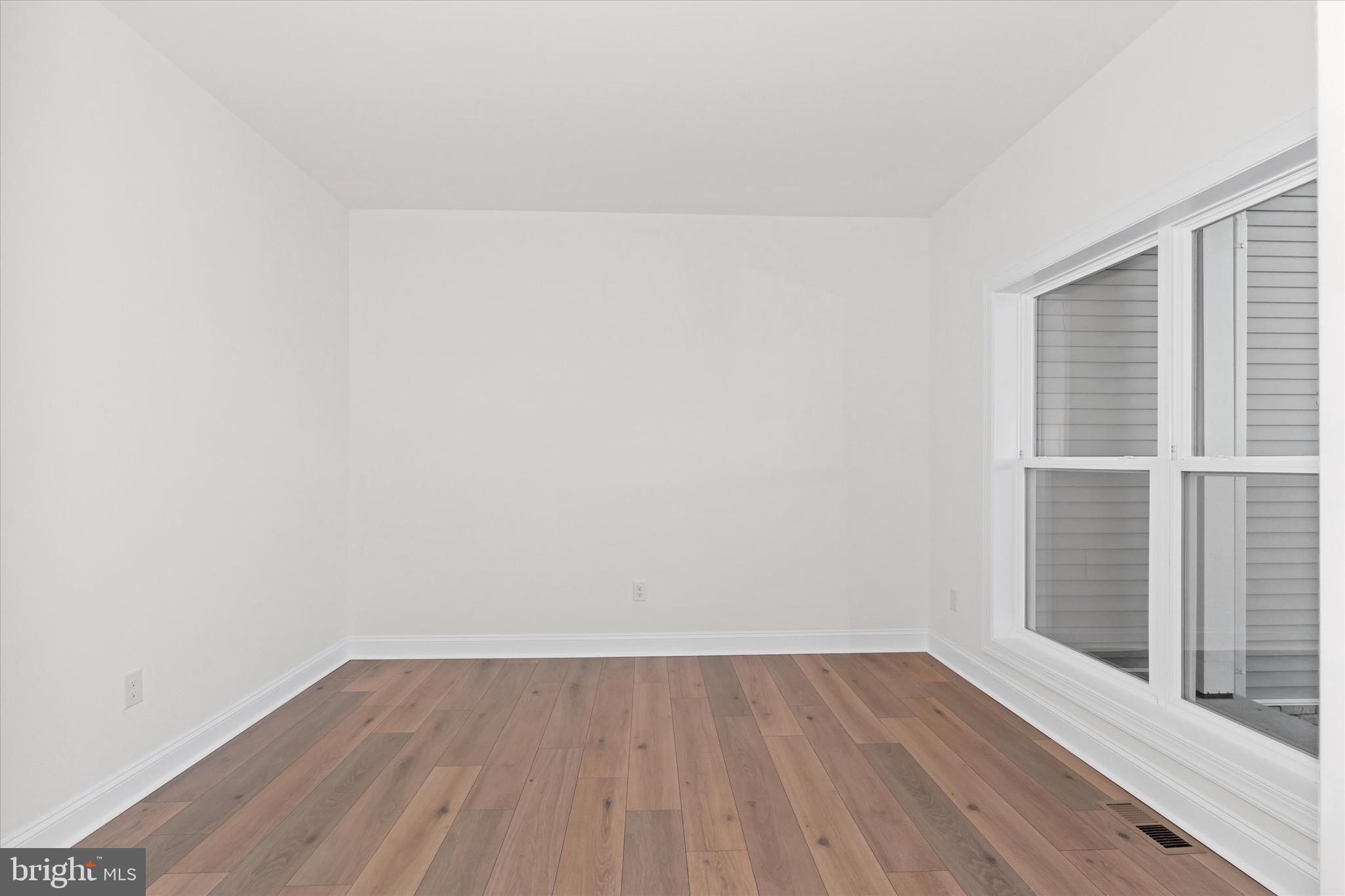 22484 Hummingbird Road, Unit 13 Ellendale, DE 19941 - Photo 24 of 34 a view of an empty room with wooden floor and a window