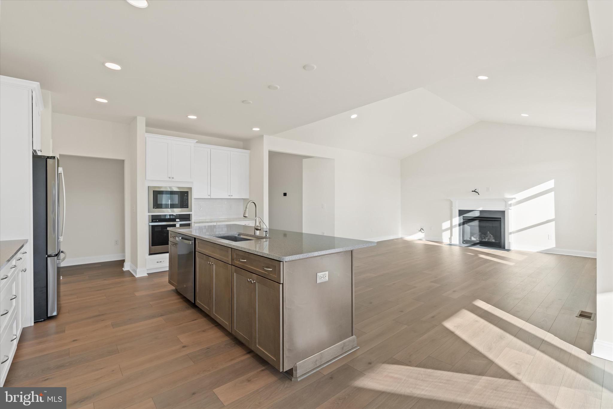 22484 Hummingbird Road, Unit 13 Ellendale, DE 19941 - Photo 3 of 34 a large kitchen with stainless steel appliances kitchen island granite countertop a large counter top and a stove top oven