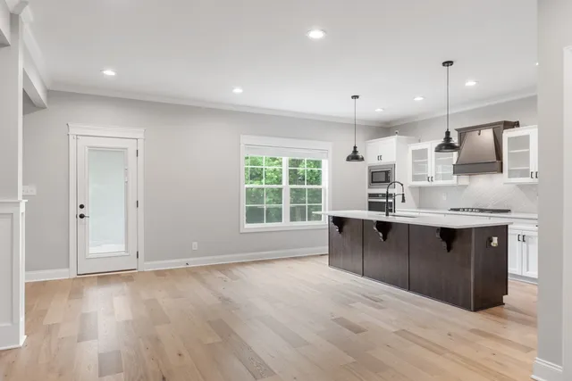 a large kitchen with kitchen island a sink wooden floor and glass window
