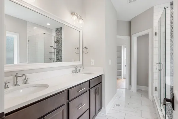 a bathroom with a sink double vanity granite tub shower and a mirror