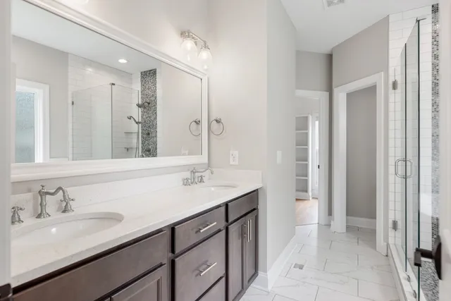 a bathroom with a sink double vanity granite tub shower and a mirror