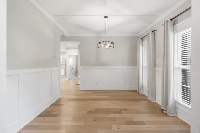 a view of a hallway with wooden floor and chandelier