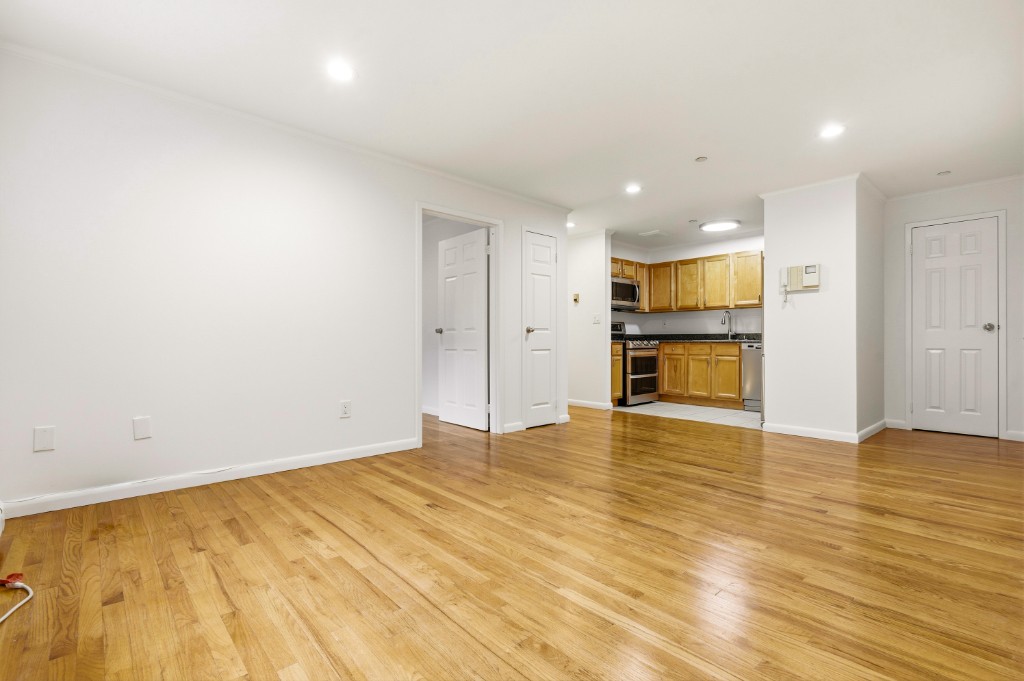 118-82 Metropolitan Avenue, Unit 3A Queens, NY 11415 - Photo 6 of 19 a view of empty room with wooden floor and kitchen view