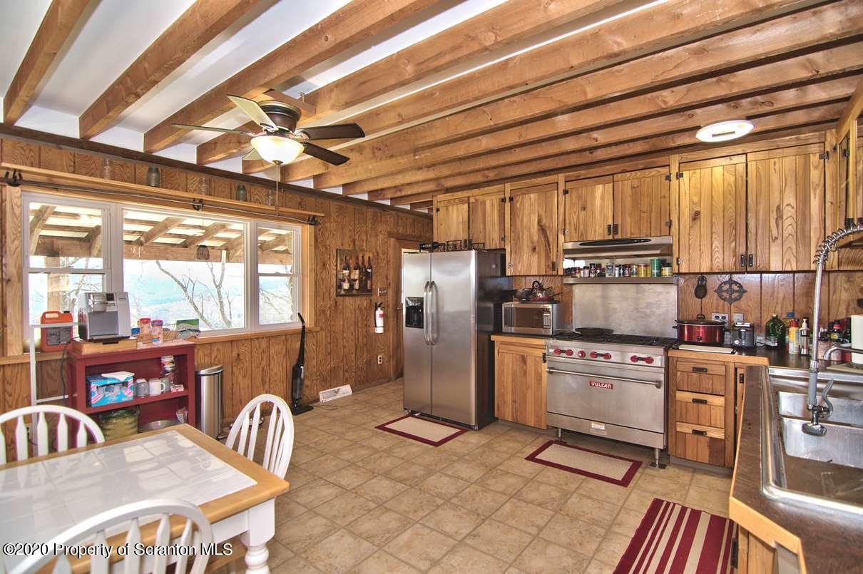 293 State Rte 1002 Tunkhannock, PA 18657 - Photo 14 of 71 a kitchen with stainless steel appliances granite countertop a stove a refrigerator a sink a dining table and chairs with wooden floor