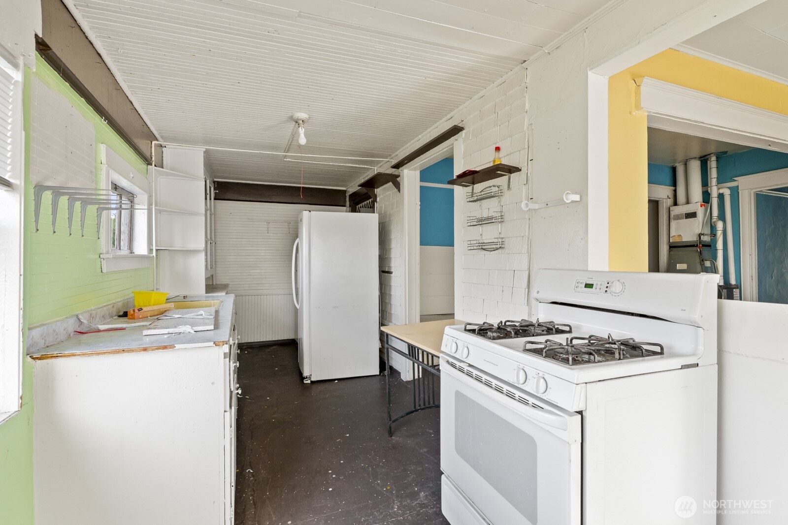 4812 46th Avenue Southwest Seattle, WA 98116 - Photo 17 of 26 a kitchen with refrigerator a stove a sink dishwasher and white cabinets with wooden floor