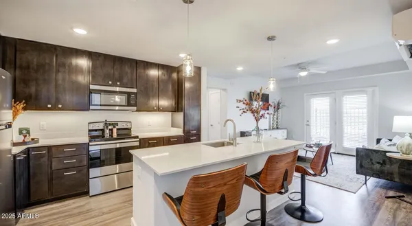 a kitchen with stainless steel appliances kitchen island granite countertop a sink a stove a refrigerator cabinets and dining table