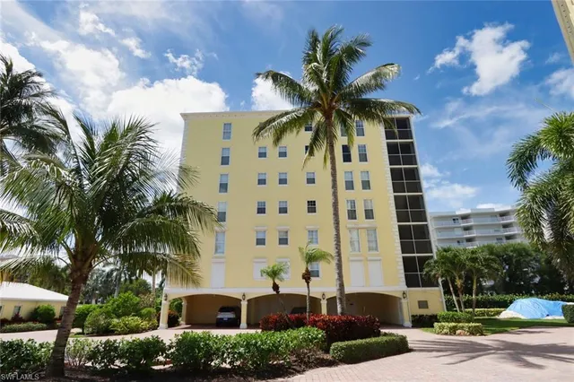 a front view of multi story residential apartment building with yard and parking space