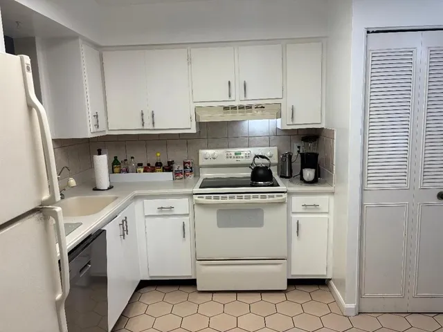 a kitchen with white cabinets appliances and a sink