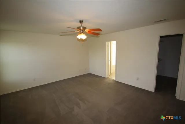 an empty room with windows and ceiling fan