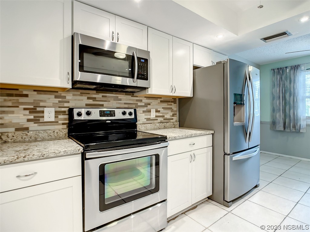 865 North Ridgewood Avenue Ormond Beach, FL 32174 - Photo 16 of 32 a kitchen with stainless steel appliances granite countertop a stove microwave and refrigerator