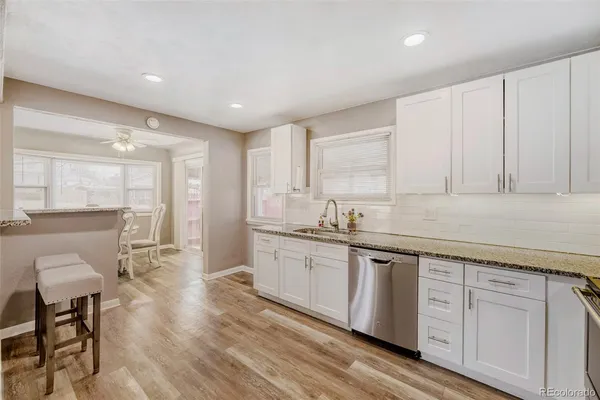 a large kitchen with kitchen island white cabinets and stainless steel appliances