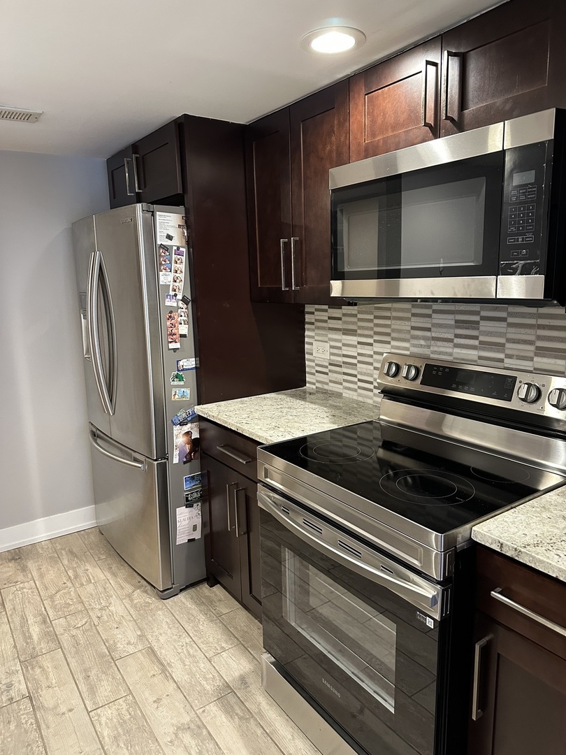9830 Sayre Avenue, Unit 13 Chicago Ridge, IL 60415 - Photo 12 of 34 a kitchen with granite countertop a refrigerator and a stove top oven