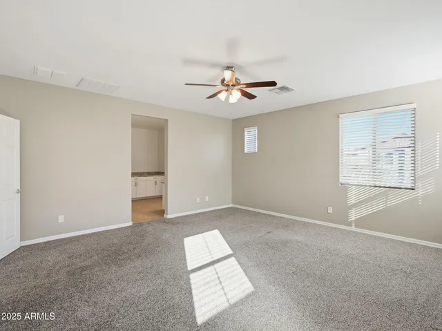 an empty room with windows and chandelier fan