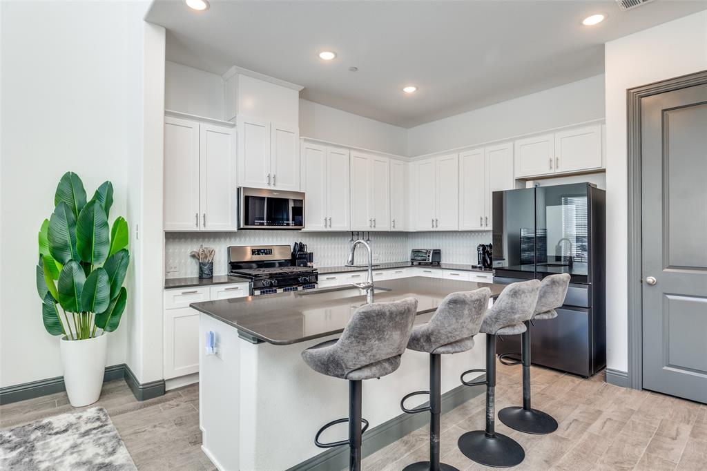 8132 Foraker Street Frisco, TX 75034 - Photo 7 of 25 Kitchen featuring white cabinetry, a kitchen breakfast bar, stainless steel appliances, an island with sink, and recessed lighting