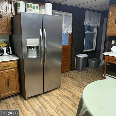 a kitchen with stainless steel appliances granite countertop a refrigerator a stove and a sink with wooden floor