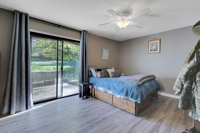 a bedroom with a bed and a large window with wooden floor