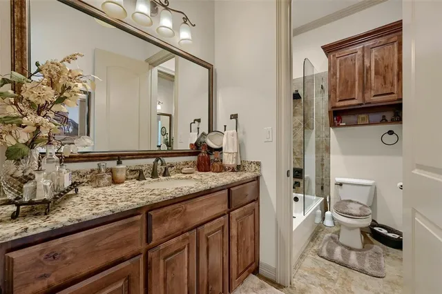a bathroom with a granite countertop sink a toilet and a mirror