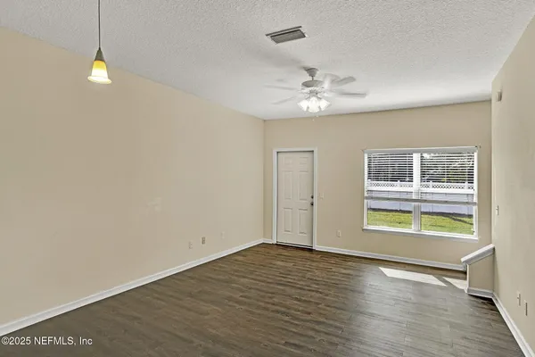an empty room with wooden floor chandelier fan and windows