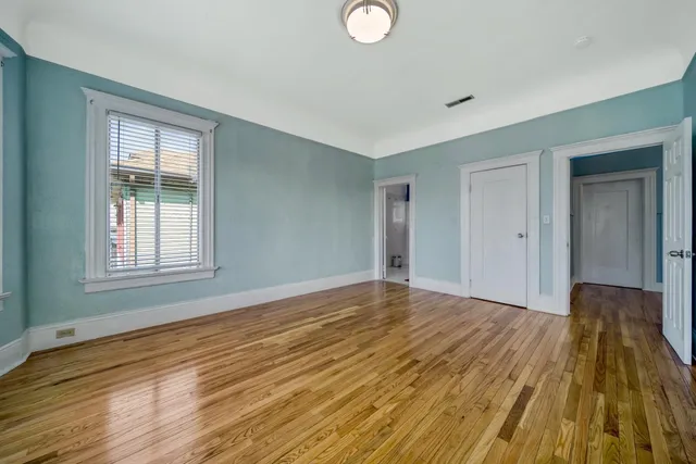 a view of empty room with wooden floor and fan