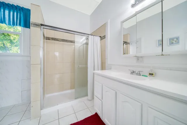 a bathroom with a shower sink vanity and mirror