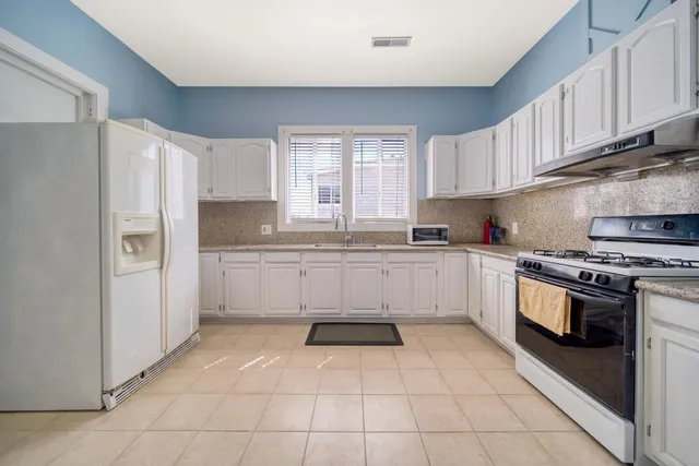a white kitchen with granite countertop stainless steel appliances