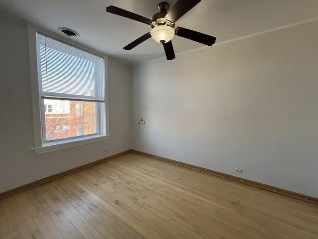 an empty room with wooden floor fan and windows