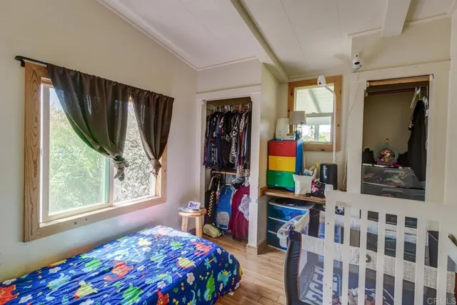 a bedroom with a bed a painting on the wall and a window