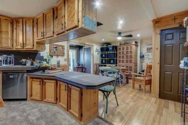 a kitchen with stainless steel appliances granite countertop a refrigerator a sink dishwasher a stove and a dining table with wooden floor