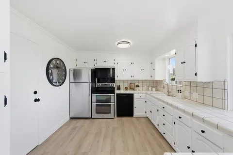a kitchen with stainless steel appliances a stove a sink and a refrigerator with white cabinets