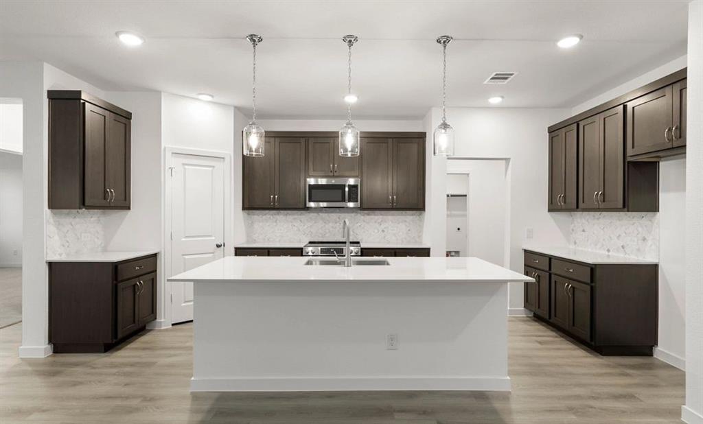 1005 Colgate Circle Princeton, TX 75407 - Photo 23 of 40 a large kitchen with stainless steel appliances kitchen island granite countertop a stove a sink and a microwave