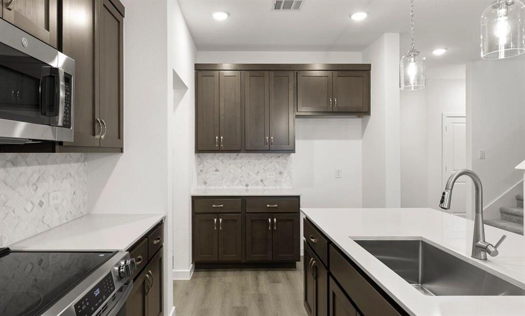 1005 Colgate Circle Princeton, TX 75407 - Photo 27 of 40 a kitchen with granite countertop a sink and a stove top oven with wooden floor