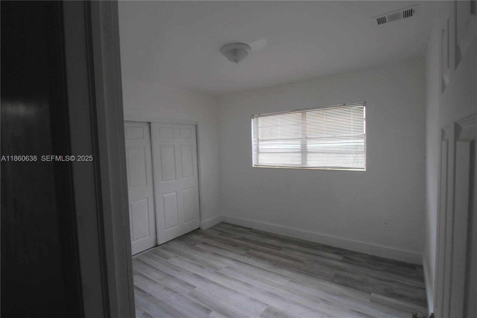 965 West 23rd Street Hialeah, FL 33010 - Photo 12 of 16 a view of an empty room with wooden floor and a window