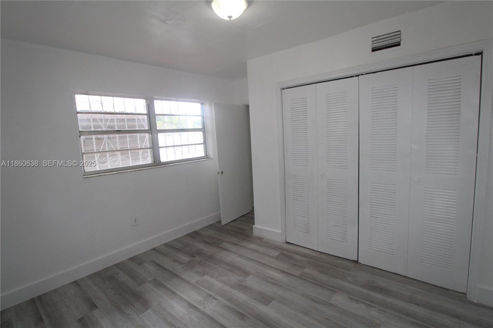 965 West 23rd Street Hialeah, FL 33010 - Photo 10 of 16 an empty room with wooden floor closet and windows