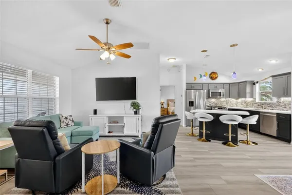 a living room with furniture a flat screen tv and kitchen view
