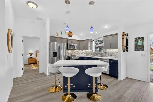 a kitchen with stainless steel appliances kitchen island granite countertop a table chairs and a refrigerator
