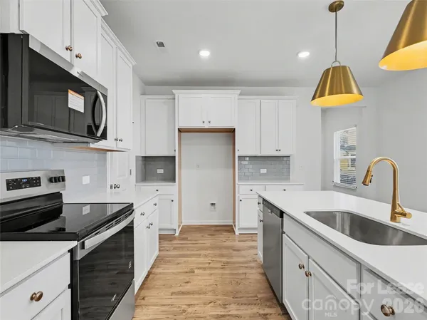 a kitchen with stainless steel appliances a sink a stove oven a counter space and cabinets