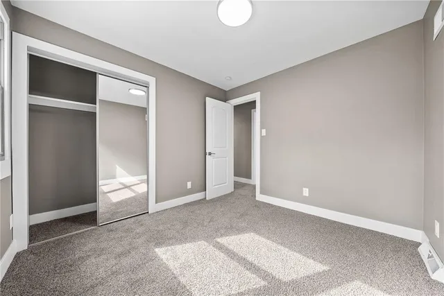 a view of an empty room with window and closet area