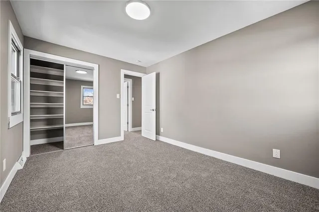 a view of an empty room with a window and a kitchen