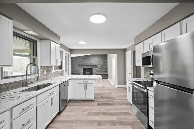 a large kitchen with stainless steel appliances kitchen island granite countertop a stove refrigerator and a sink